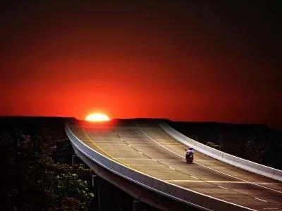 motorcycle-driving-on-empty-highway-in-sunset.webp