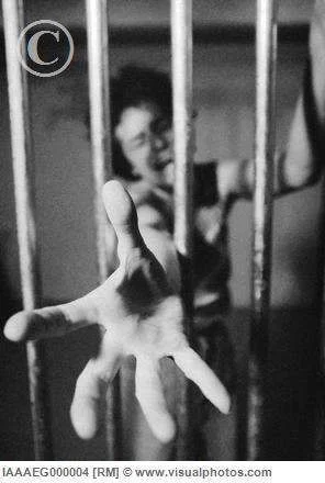 Woman_behind_prison_bars_reaching_hand_through_IAAAEG000004.webp